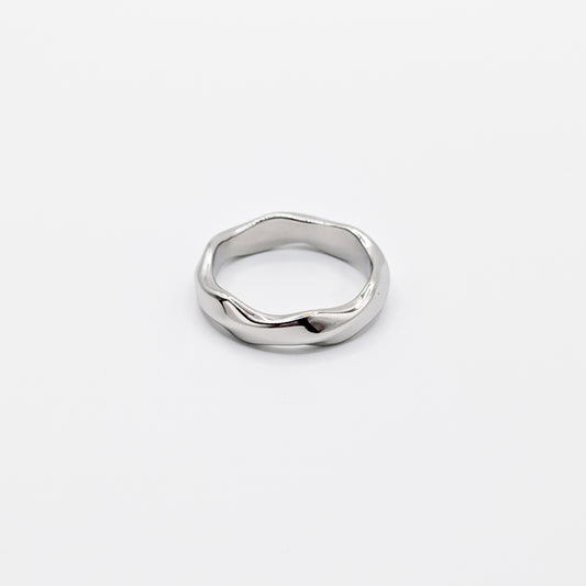 A single wavy stainless steel ring on a plain background.