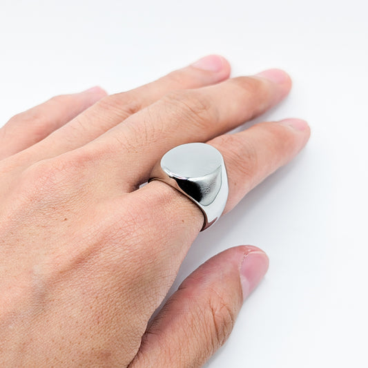 Close up of thick polished minimalist stainless steel signet ring on a model.