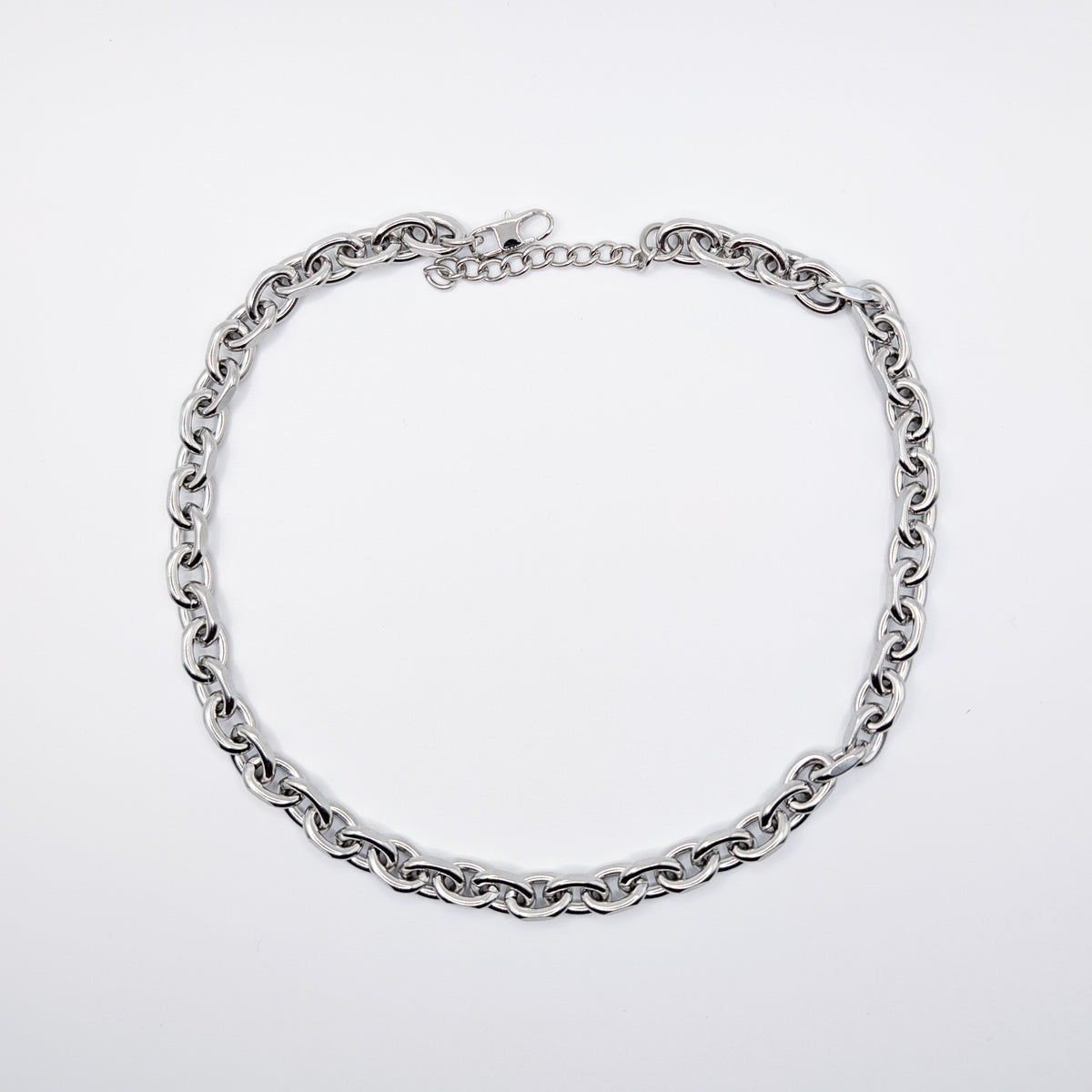 A stainless steel cable chain necklace with a lobster clasp, arranged in a circle on a plain light gray background.
