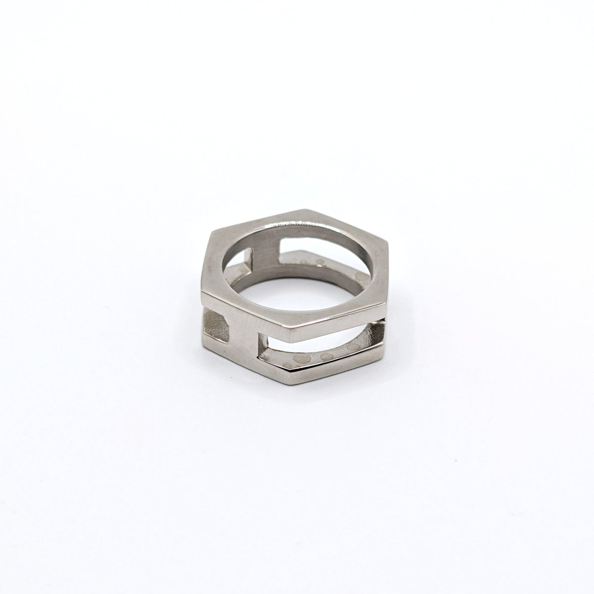 A silver-toned metal hexagonal ring with a geometric openwork design, photographed on a clean white background.