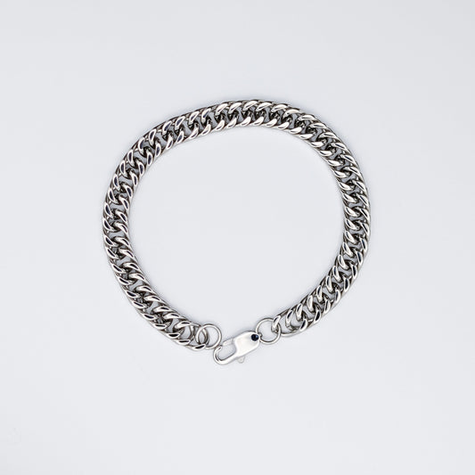 Stainless steel Cuban link style chain bracelet from a top down view, against a neutral background.