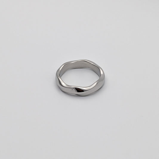 A single wavy stainless steel ring on a plain background.