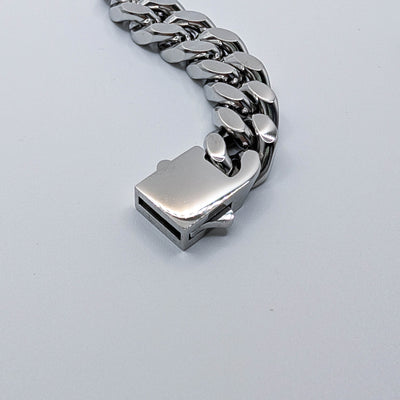Close-up view of a silver stainless steel Cuban link chain highlighting the secure rectangular locking box clasp.