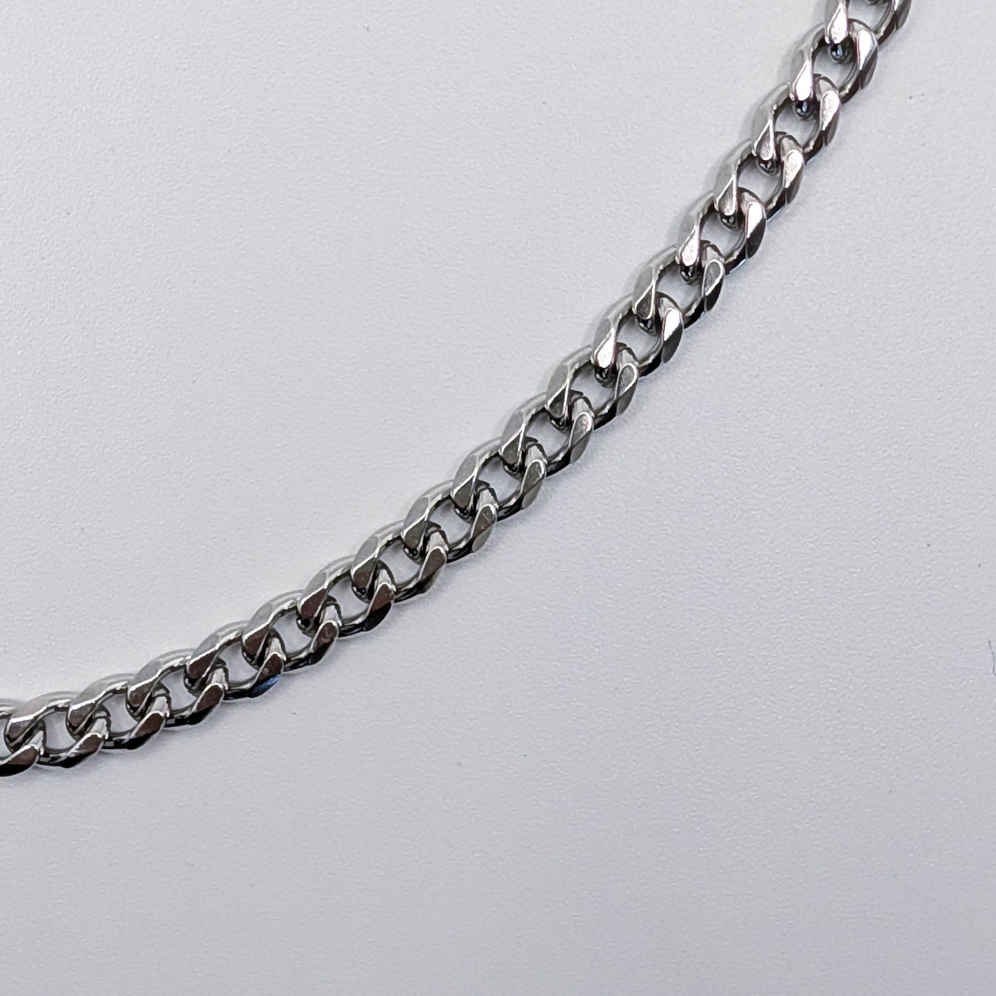 Close up of stainless steel cuban link style chain bracelet, showing the details of the chain.