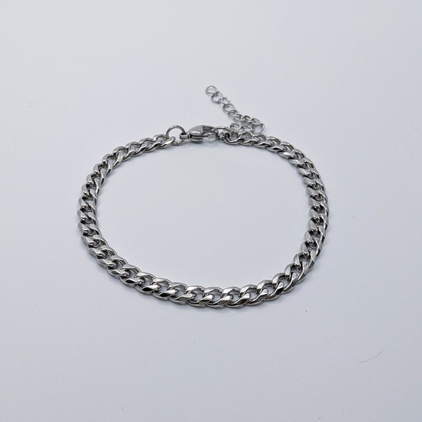 Silver stainless steel cuban link style chain bracelet on a light gray background