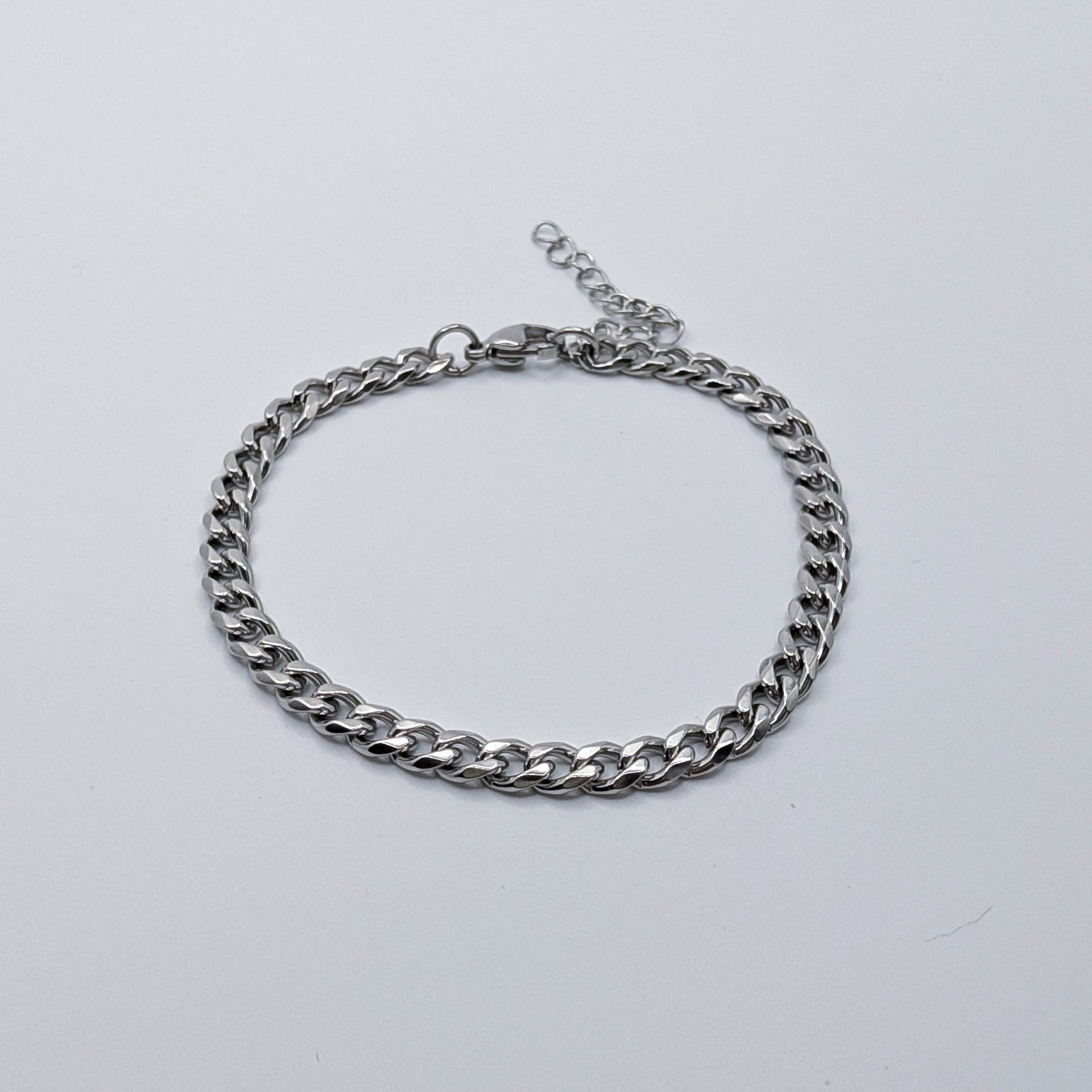 Silver stainless steel cuban link style chain bracelet on a light gray background
