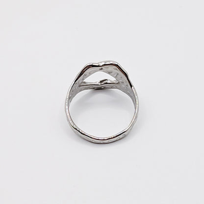 Alternative angle of textured stainless steel ring with an open cutouts on a white background.