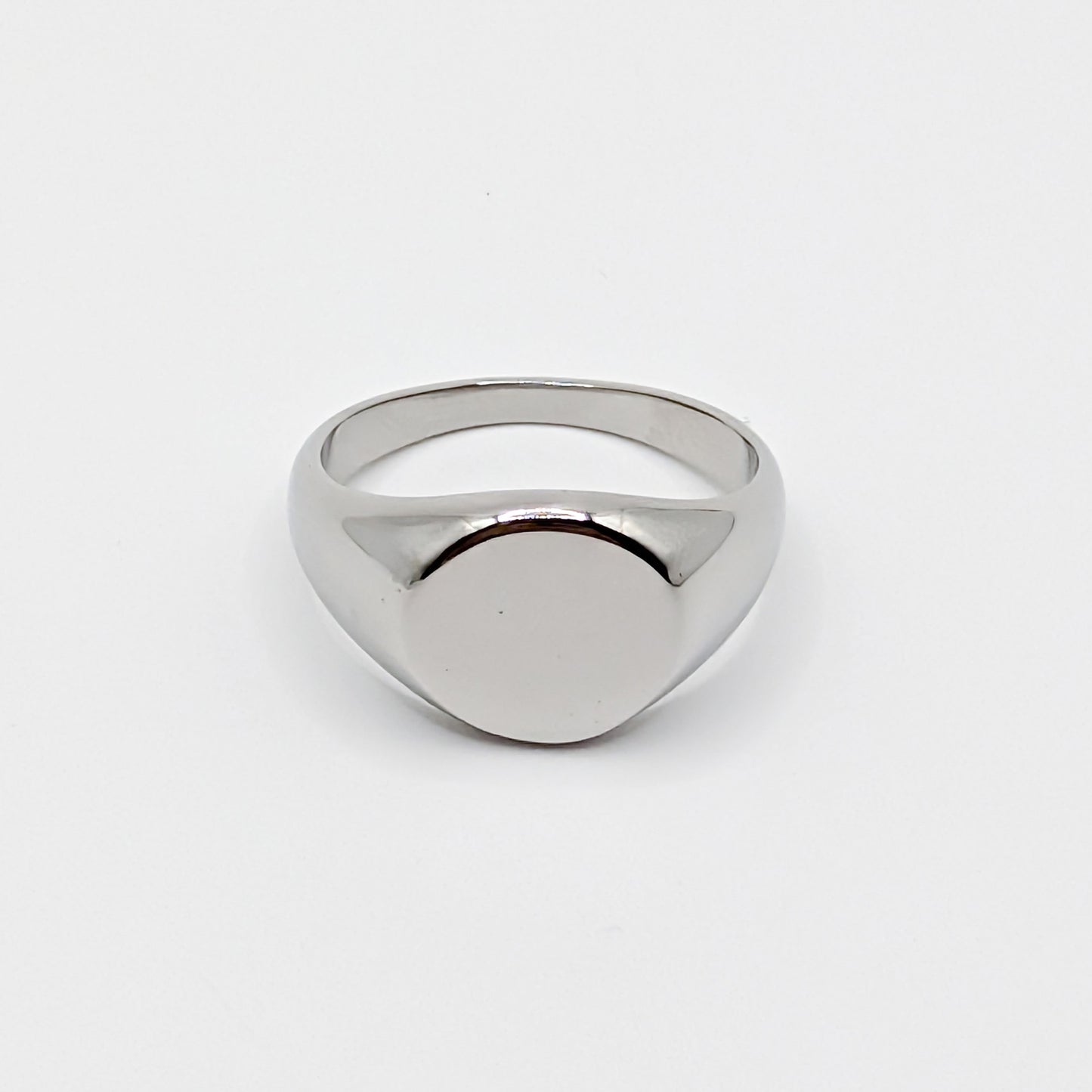 Minimalist polished stainless steel oval signet ring with a smooth blank face on a white background.