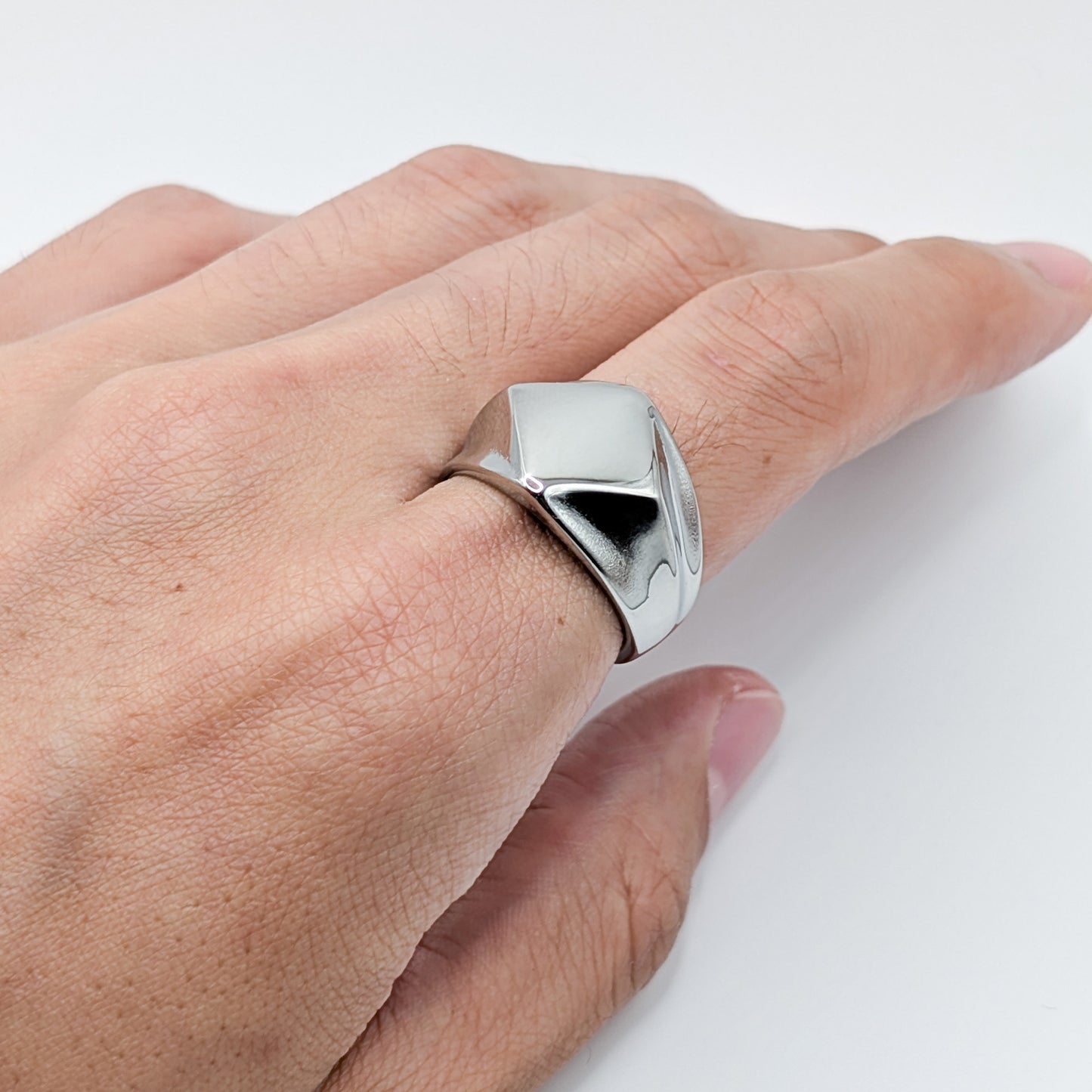 Close-up of a silver stainless steel geometric pointed ring worn on a hand.