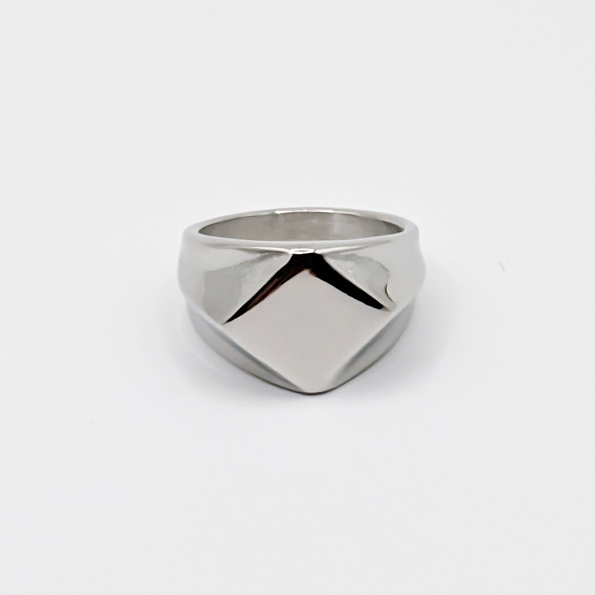 Polished minimalist stainless steel signet ring with a geometric diamond shaped pointed face on a clean white background.