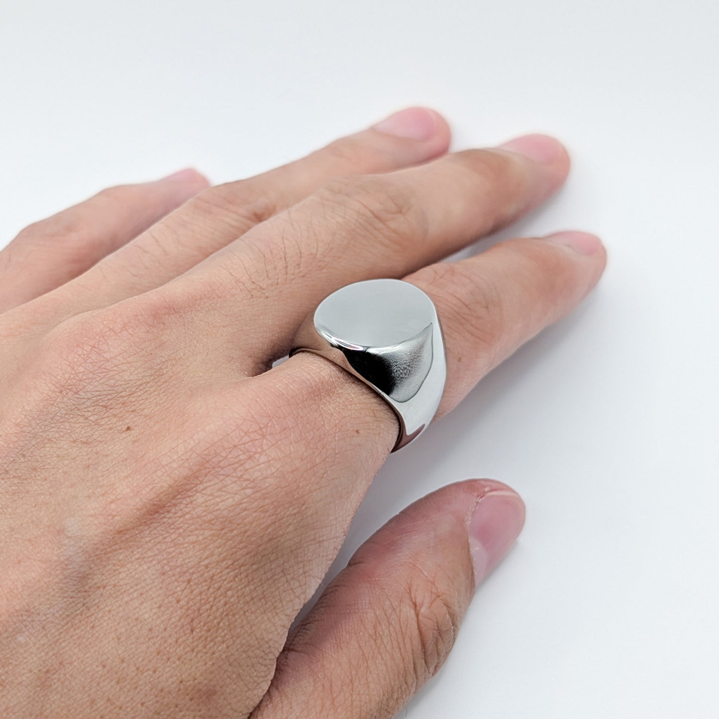 Close up of thick polished minimalist stainless steel signet ring on a model.