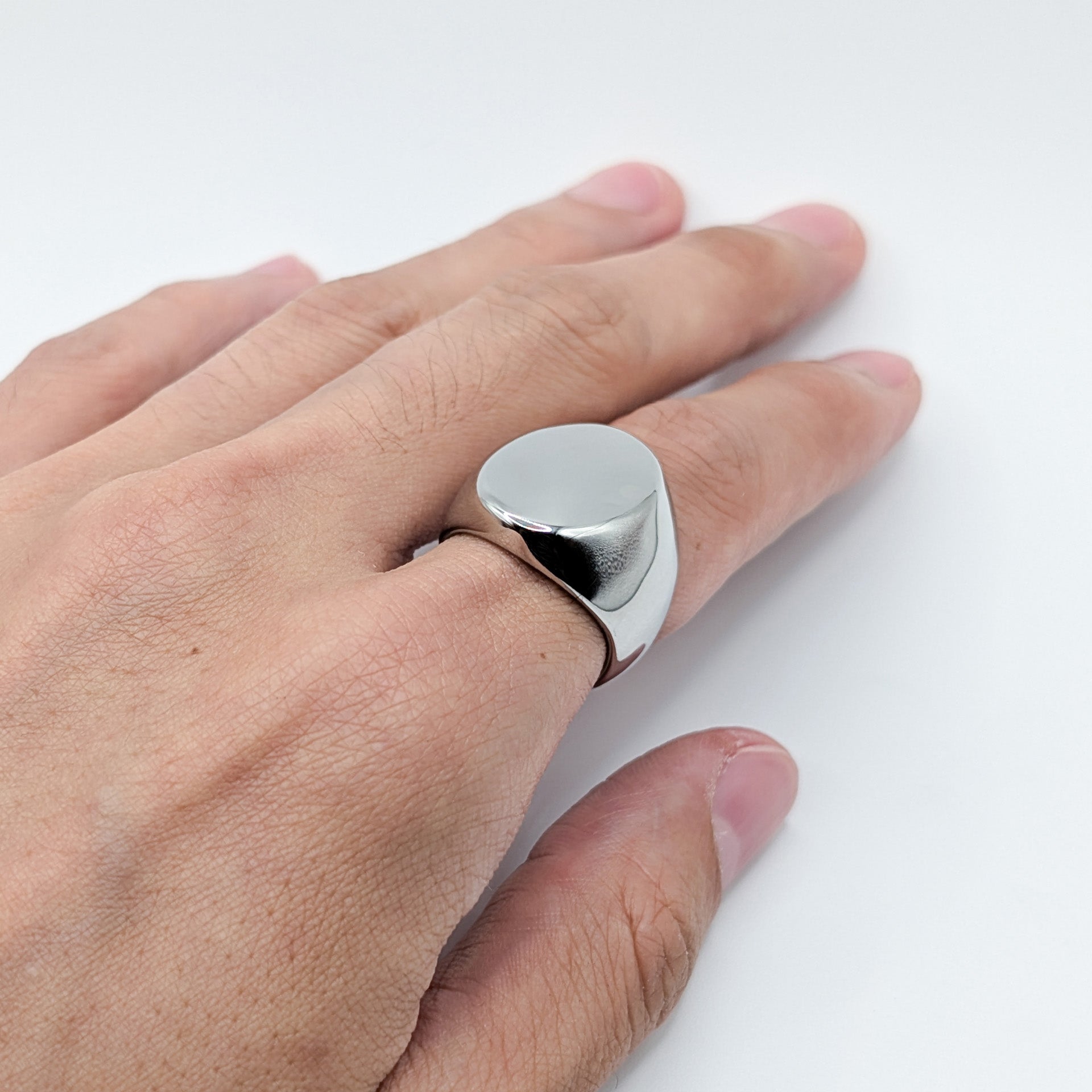 Close up of thick polished minimalist stainless steel signet ring on a model.