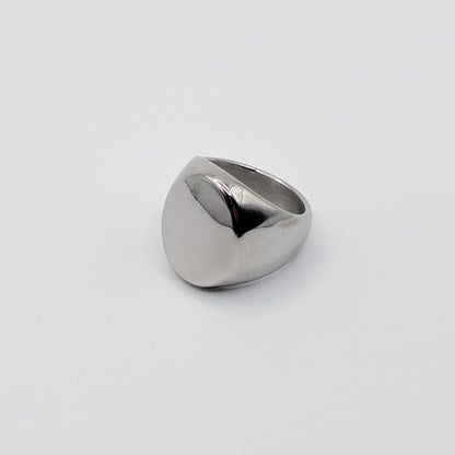 Side view of thick polished minimalist stainless steel signet ring on a white background.