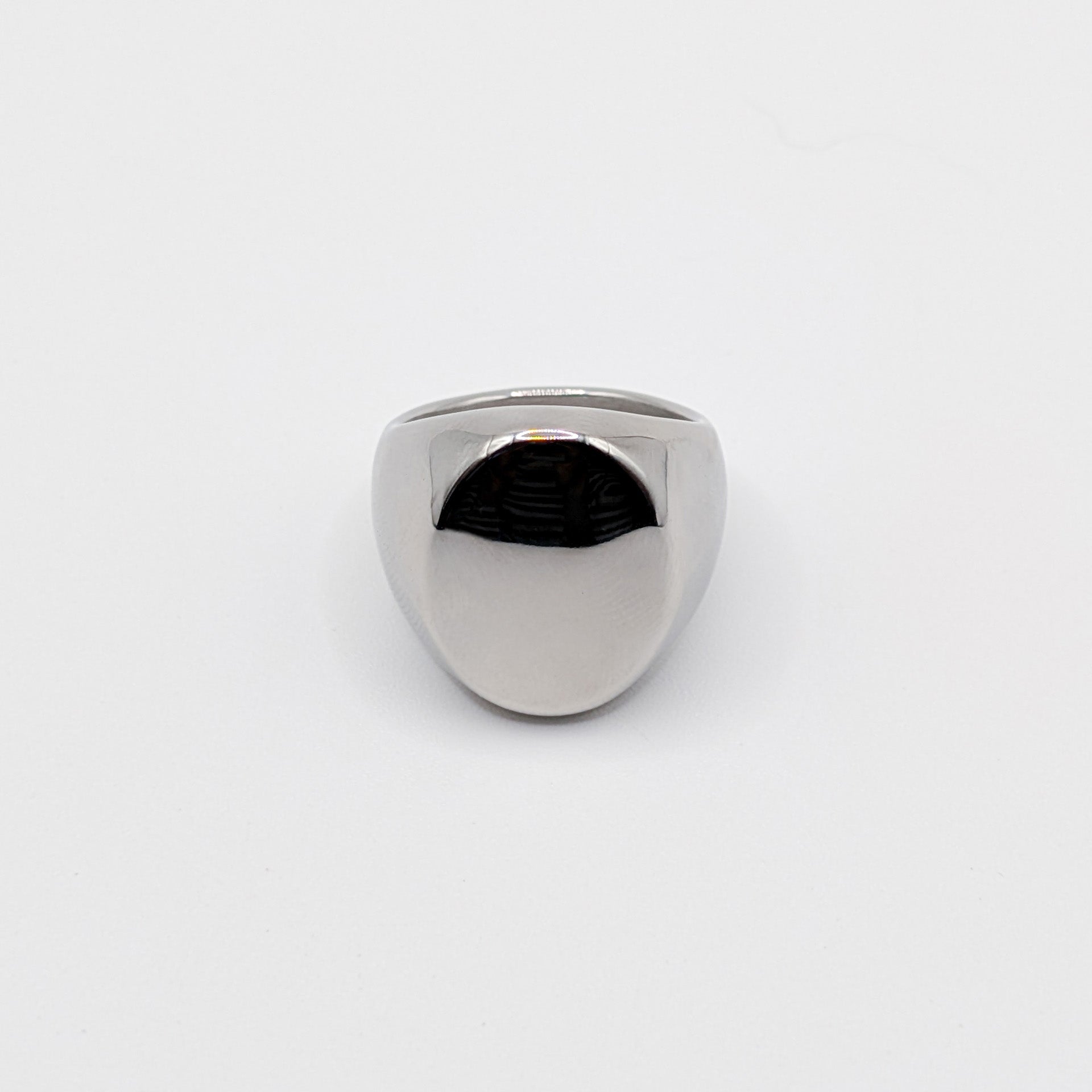 Thick polished minimalist stainless steel signet ring on a white background.