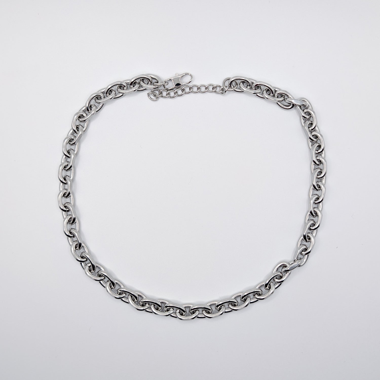 A stainless steel cable chain necklace with a lobster clasp, arranged in a circle on a plain light gray background.