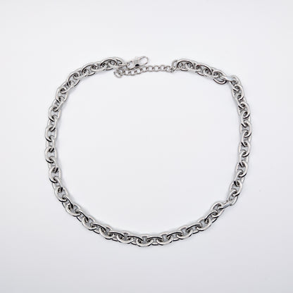 A stainless steel cable chain necklace with a lobster clasp, arranged in a circle on a plain light gray background.