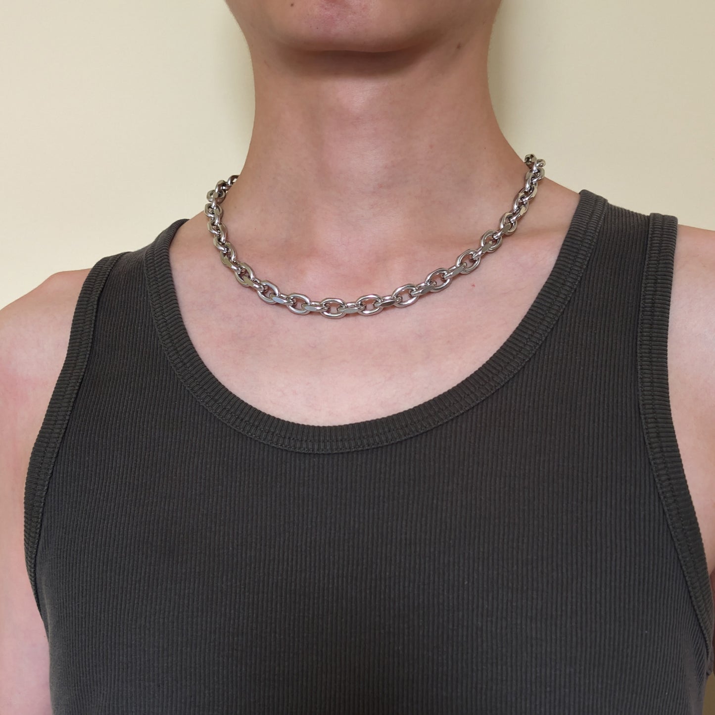 A close-up of a person wearing the stainless steel cable chain necklace over a dark charcoal ribbed tank.