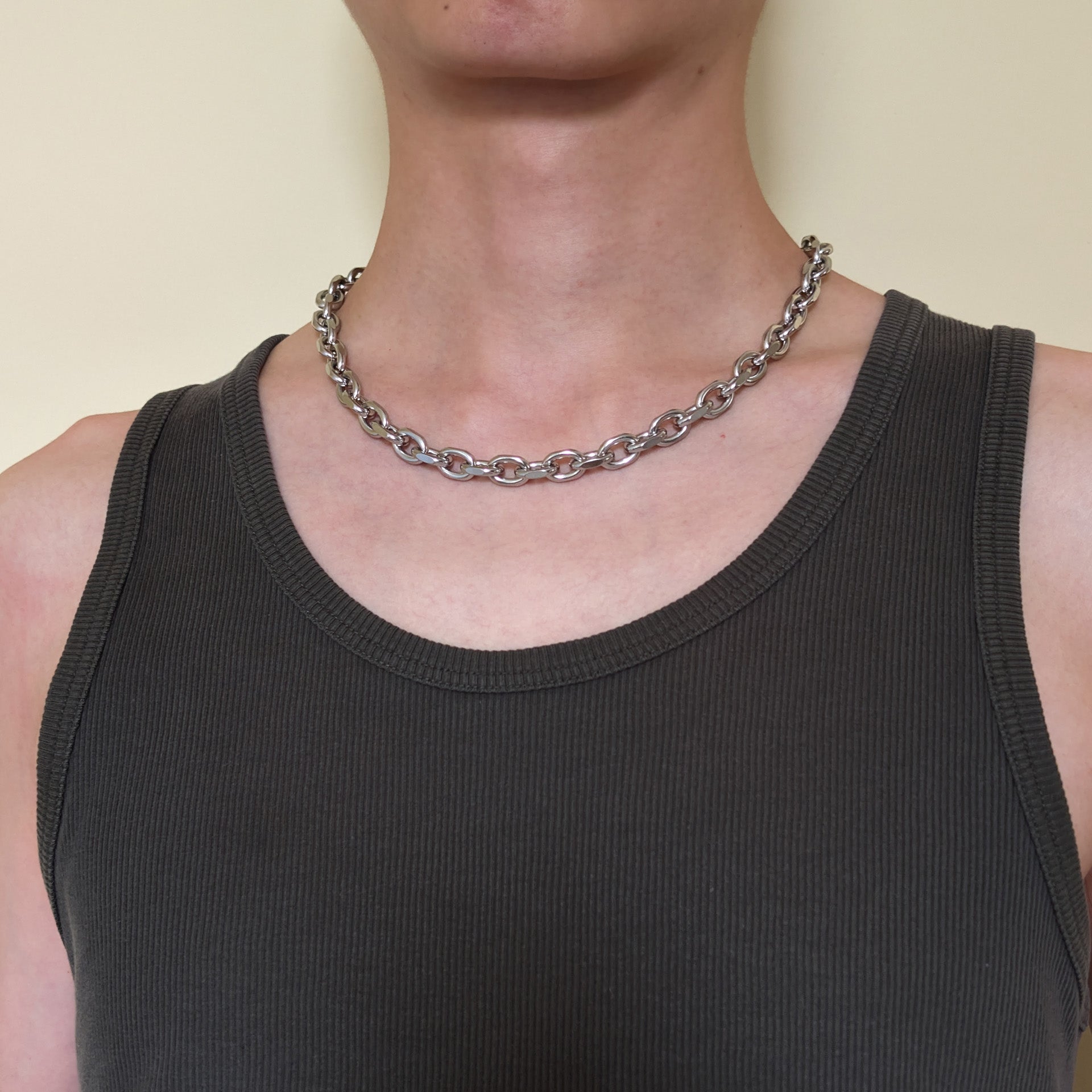 A close-up of a person wearing the stainless steel cable chain necklace over a dark charcoal ribbed tank.