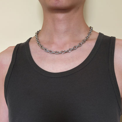A close-up of a person wearing the stainless steel cable chain necklace over a dark charcoal ribbed tank.