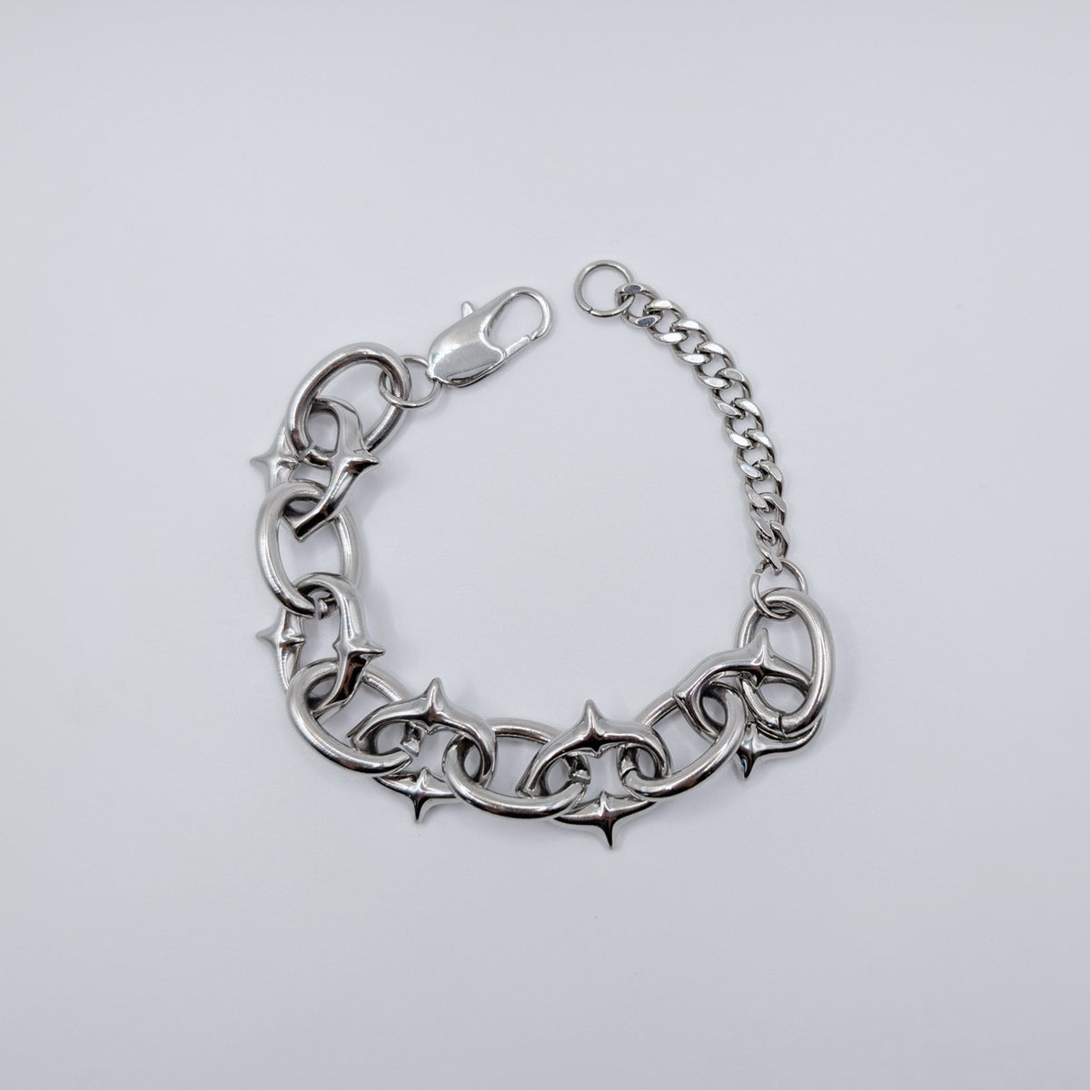 A silver-toned metal bracelet featuring interlocking star-shaped links and a short extension chain with a lobster clasp, shown on a light gray background.